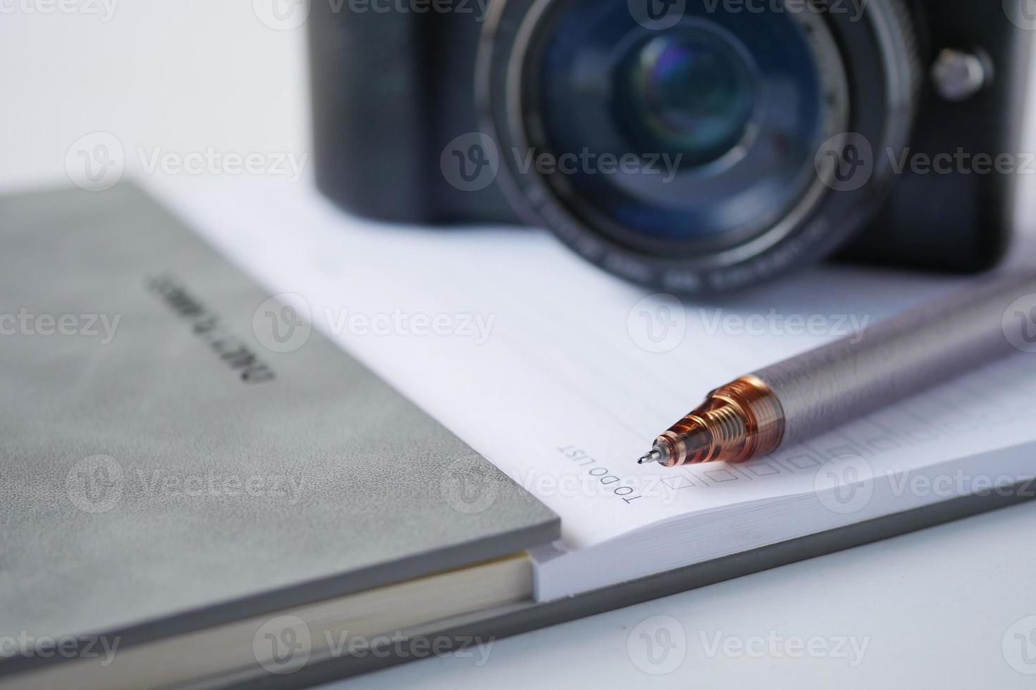 notepad, pen and camera on table photo