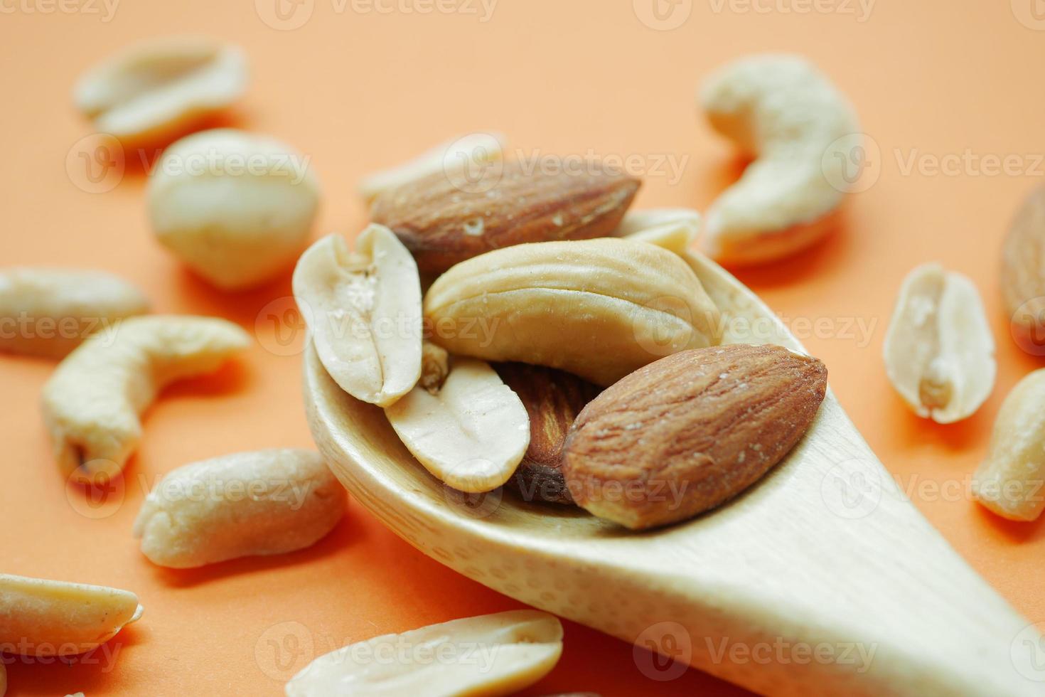 almond and cashew nuts on wooden spoon photo