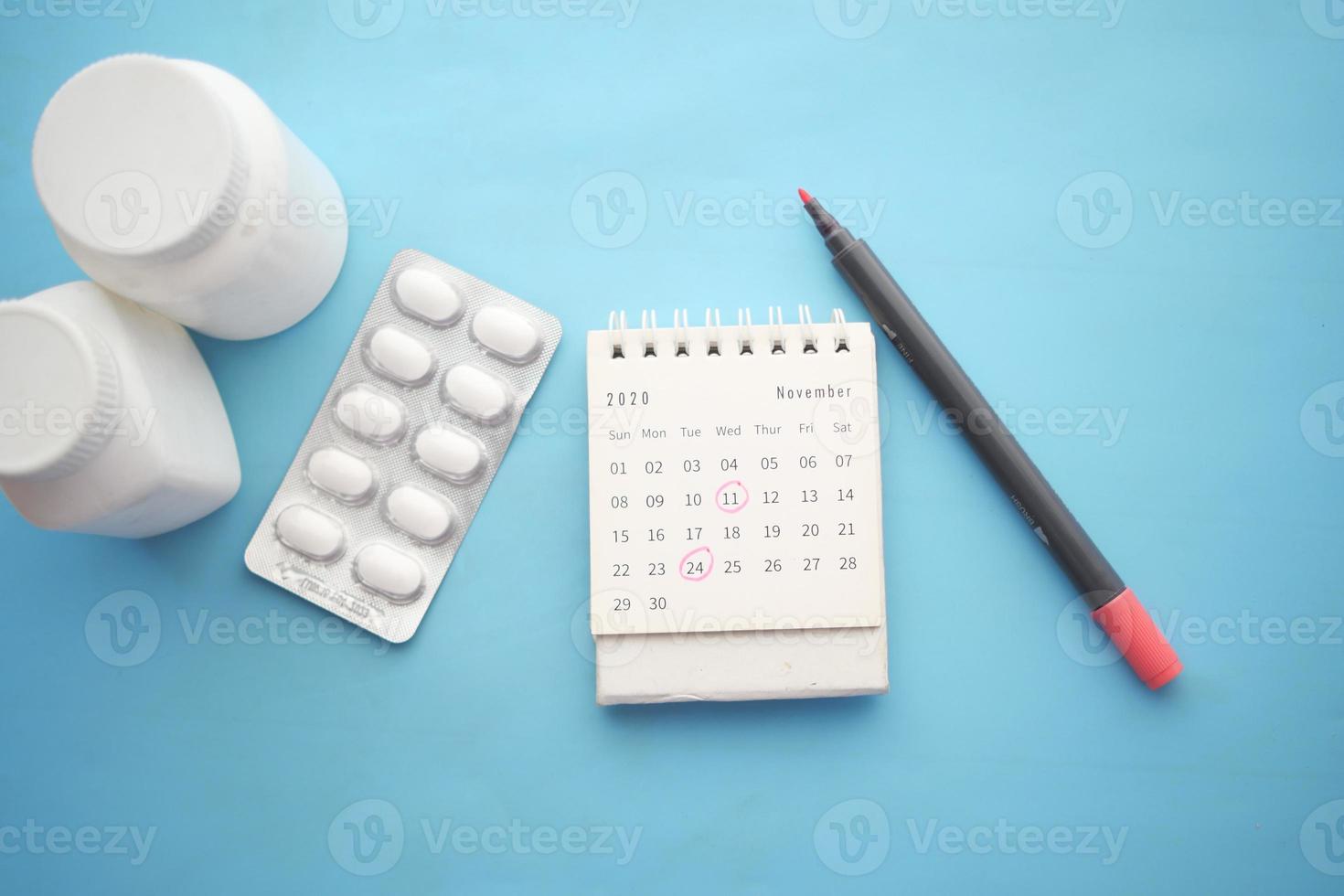 medical pill container and calendar on color background photo