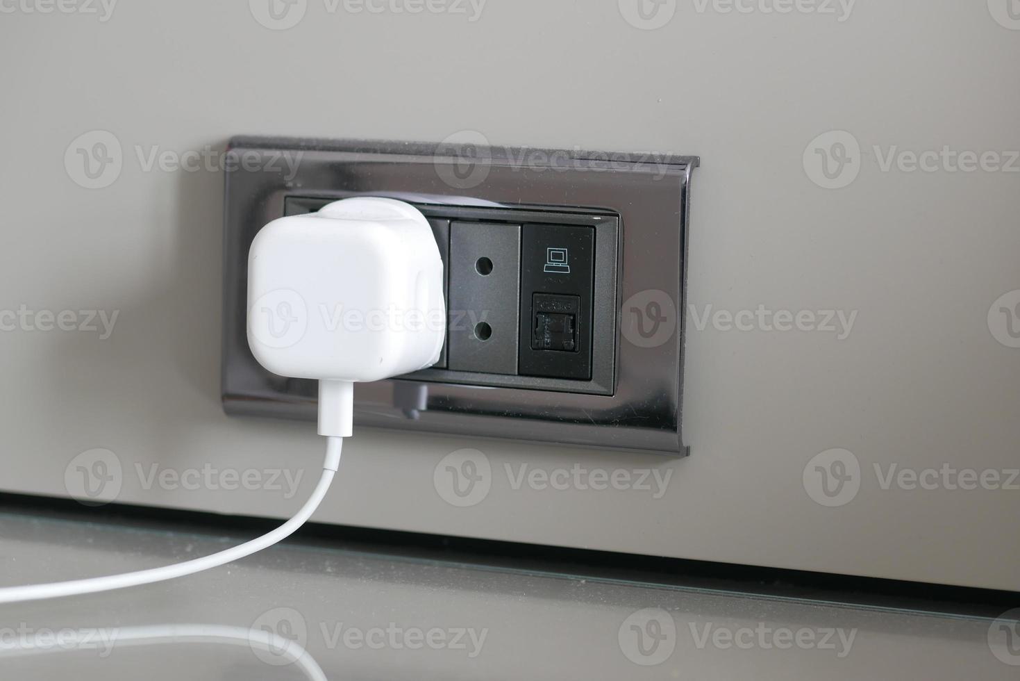white color power cord cable plugged into wall photo