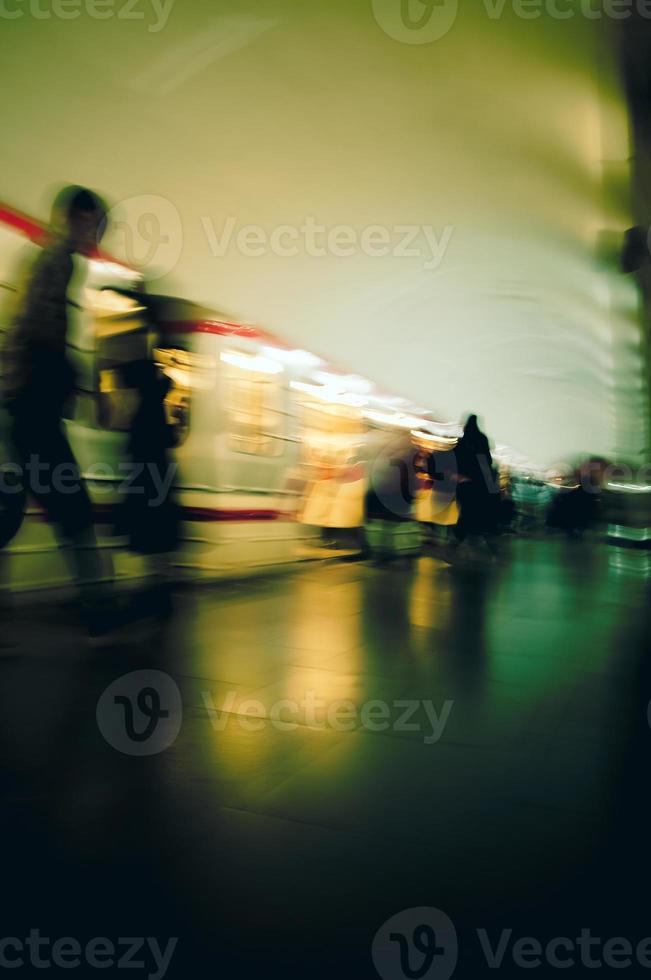 Motion blur image of a subway with moving people and a trai. photo