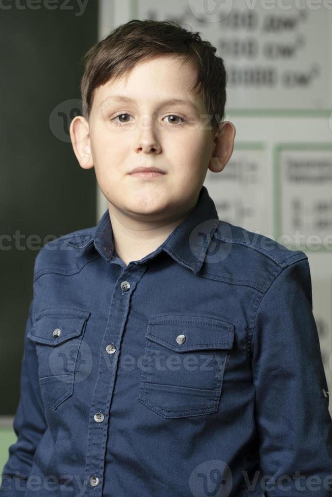 Vertical portrait of a schoolboy at the blackboard. photo