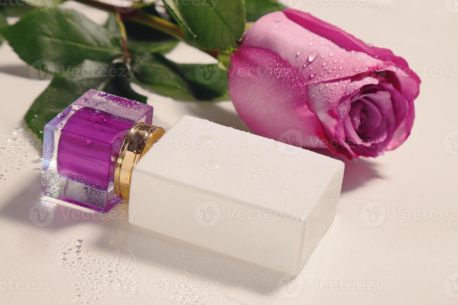 blanco perfume botella con púrpura parte superior y Rosa con agua gotas. Bosquejo foto