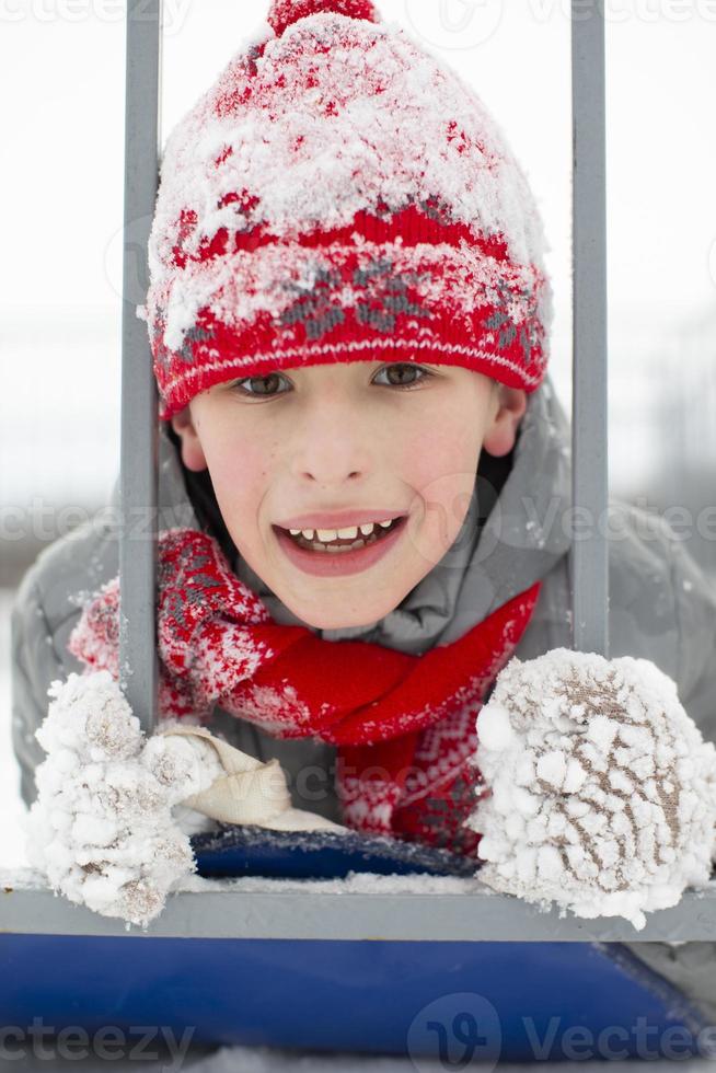 Portrait of a boy in a red winter hat covered with snow. photo