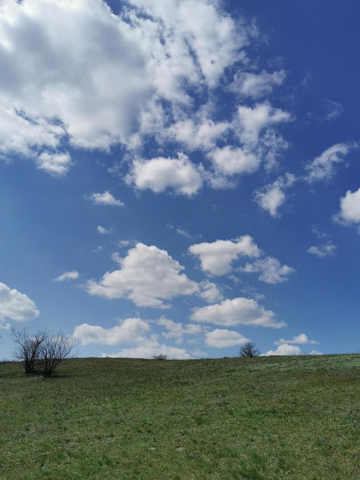Blue spring sky behind a green hill photo