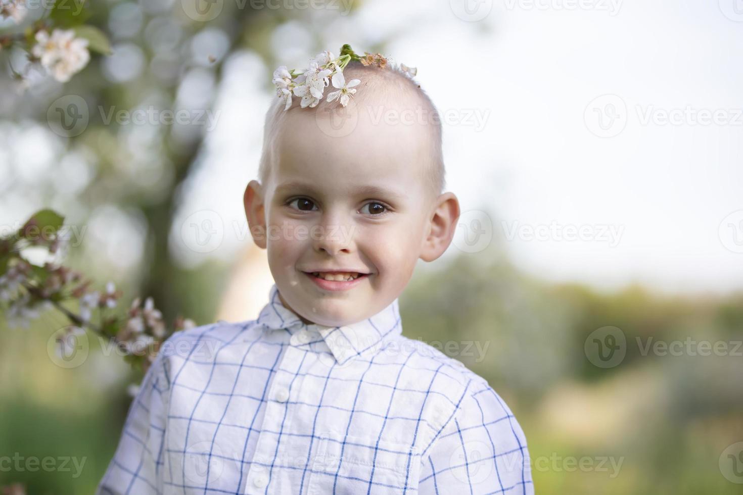 A happy child in a blooming spring garden rejoices, smiles. photo