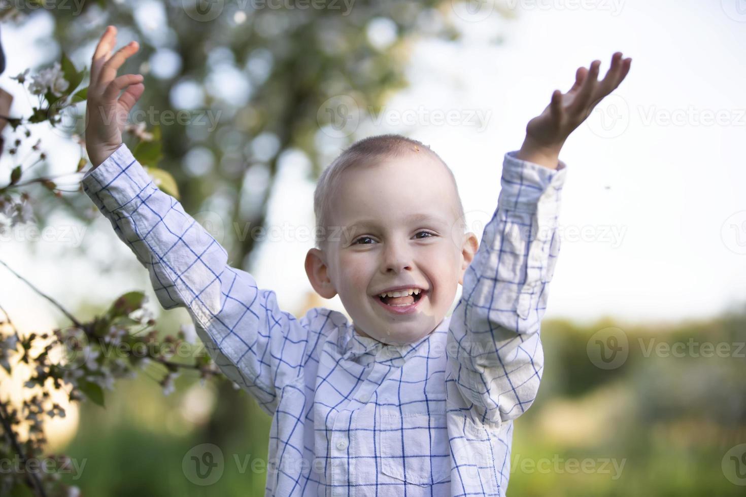 A happy child in a blooming spring garden rejoices, smiles. photo