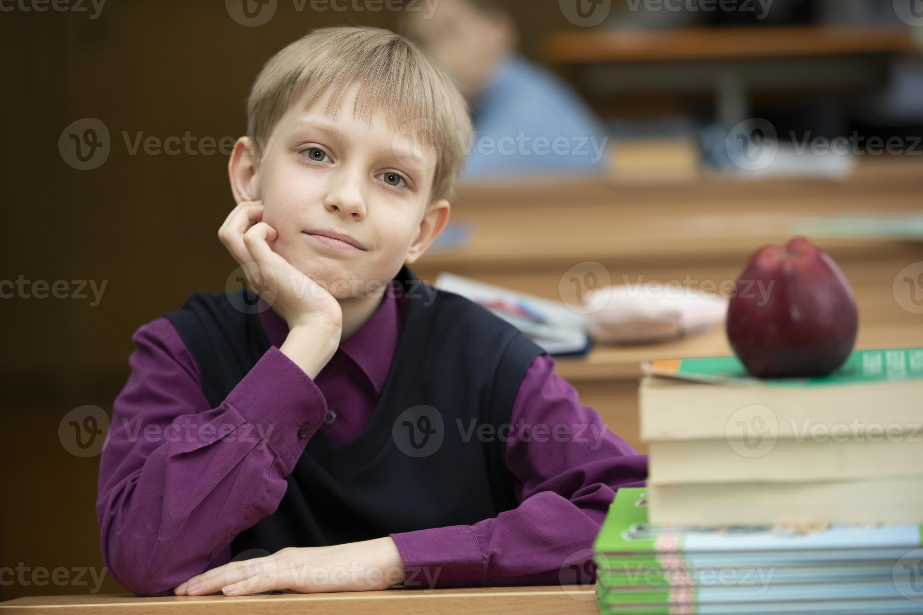 Schoolboy at the desk. Boy in the classroom with books and an apple