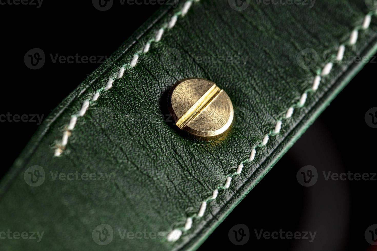 Part of a leather product or belt in green on a black background. photo