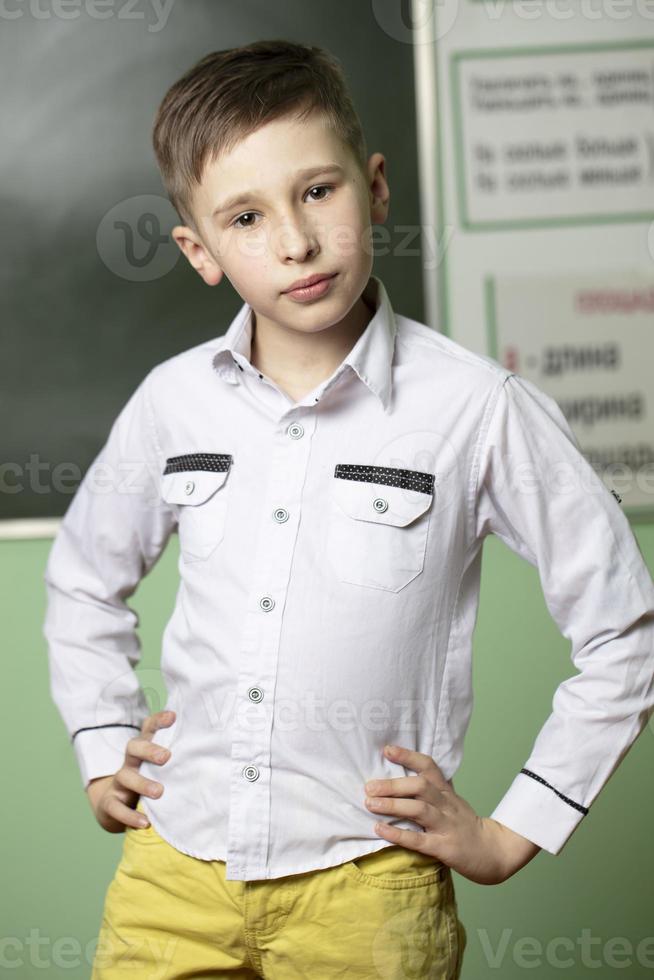 Portrait of a schoolboy at the blackboard. The boy in the classroom is looking at the camera. photo