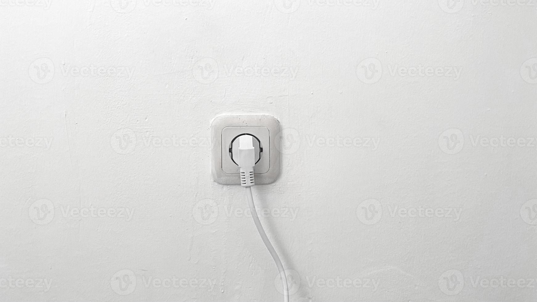 old electrical socket isolated on gray wall. power cord cable plugged into asian wall outlet on white vintage plaster wall with empty space photo