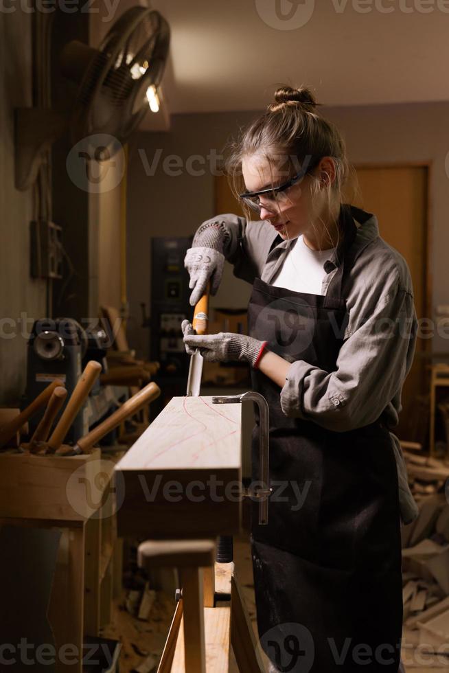 Attractive female carpenter using some power tools for her work in a woodshop photo