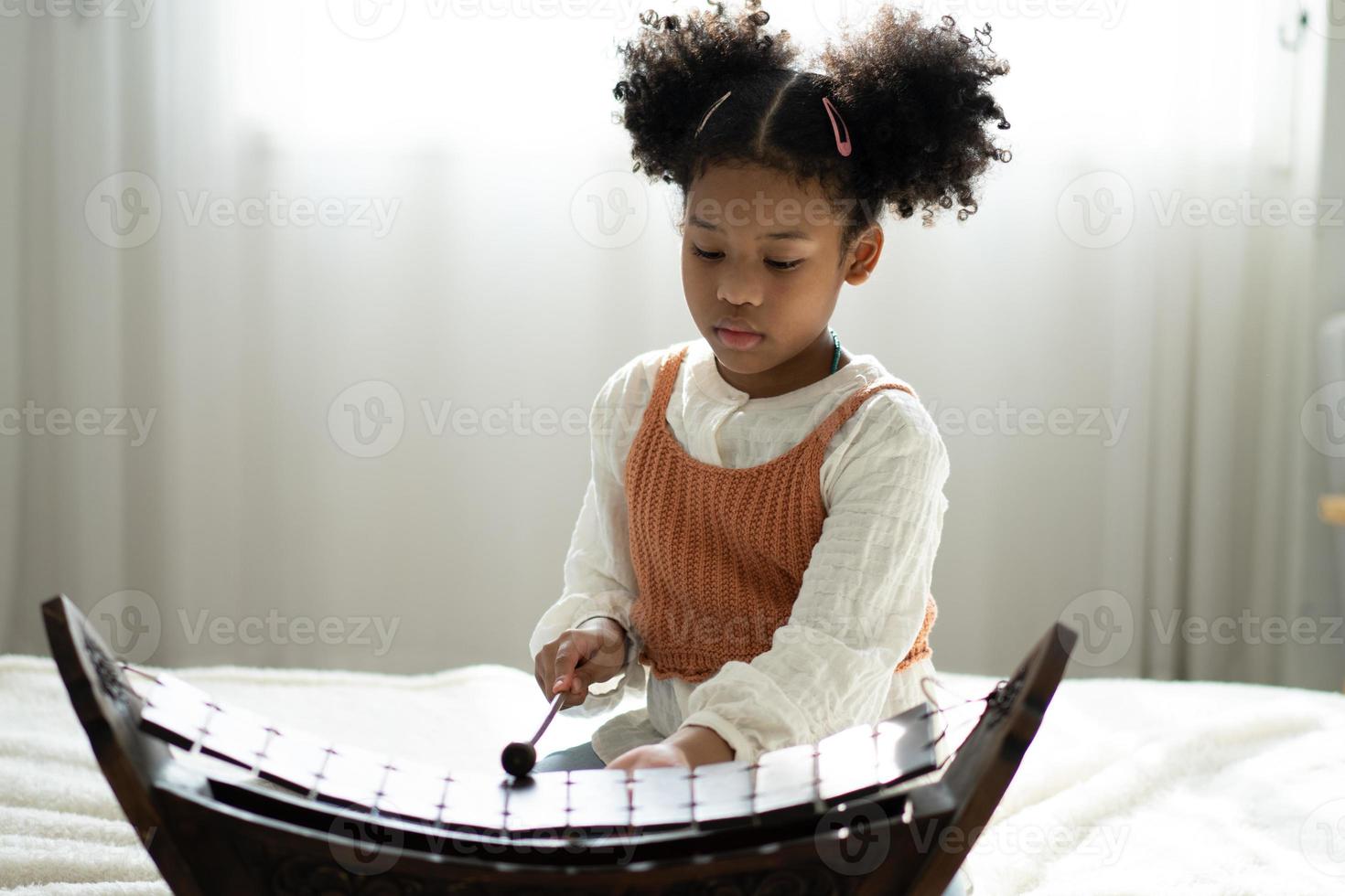 A little girl plays the xylophone in a music class. The child learns to play the xylophone photo