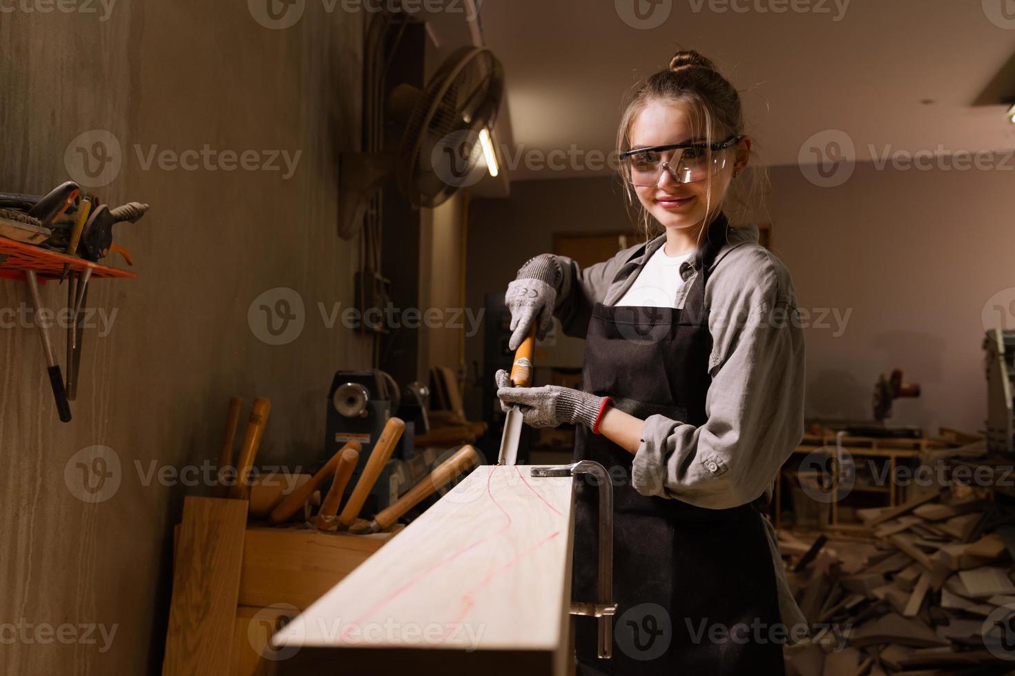 atractivo hembra carpintero utilizando algunos poder herramientas para su trabajo en un carpintería foto