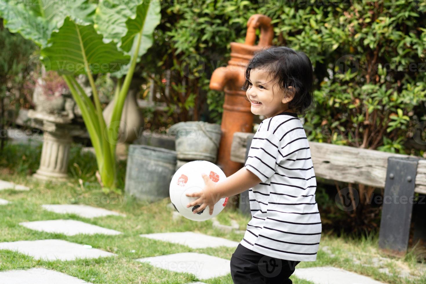 Cute little boy playing soccer with ball outdoors on soccer field photo