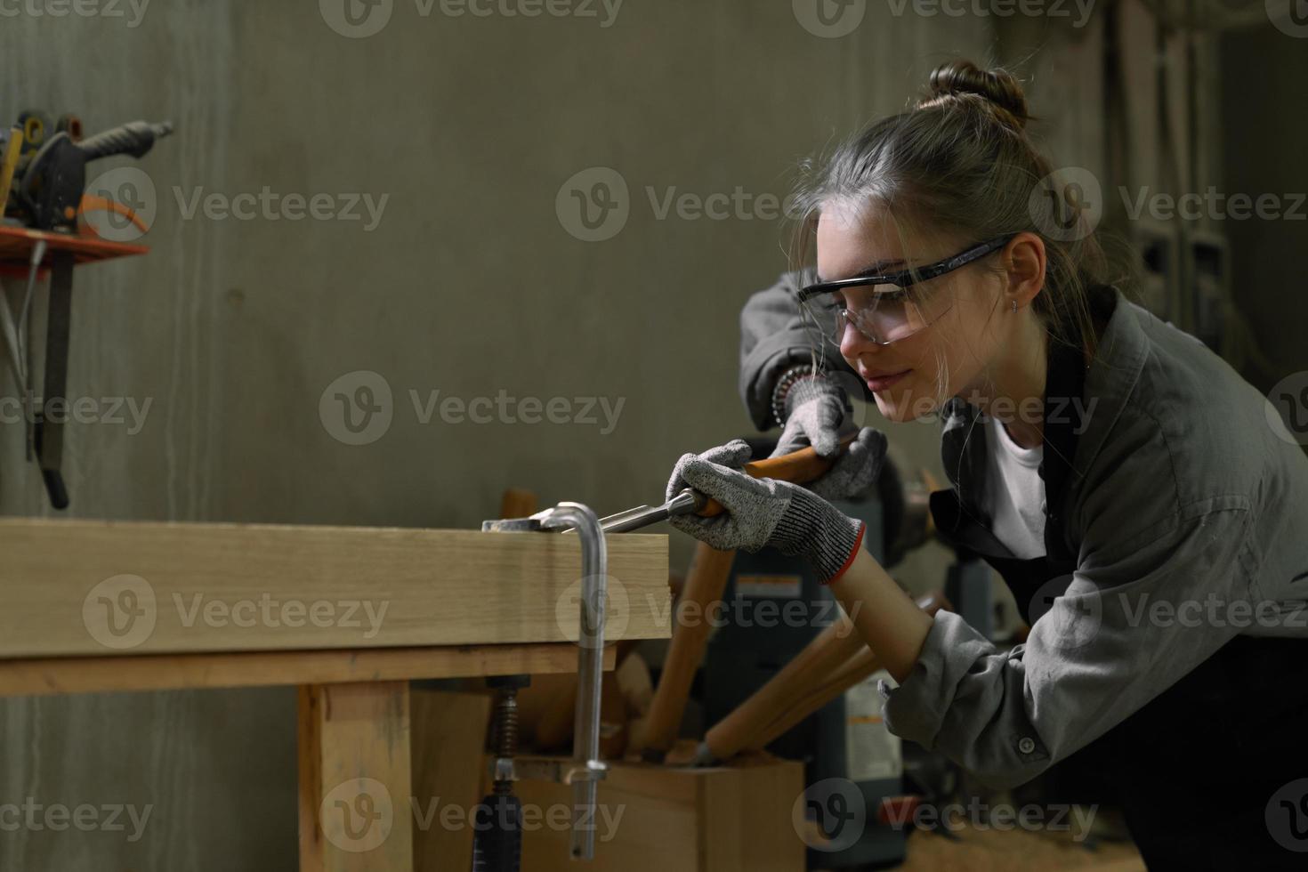 Attractive female carpenter using some power tools for her work in a woodshop photo