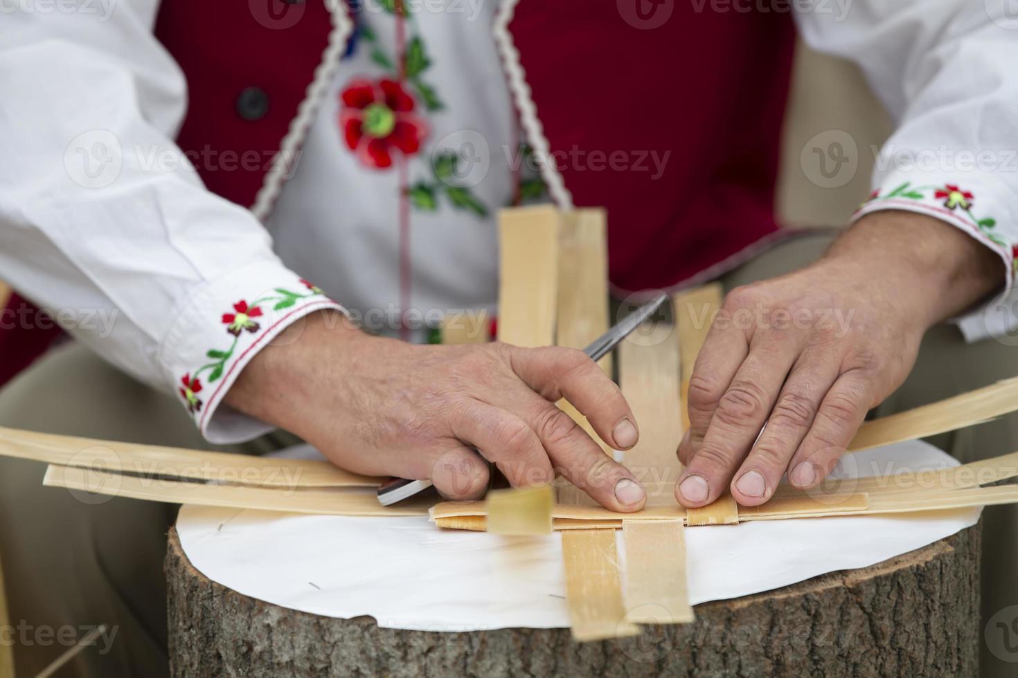 manos de el Maestro hacer productos desde abedul ladrar. Costura un cesta. étnico eslavo artesanía. foto
