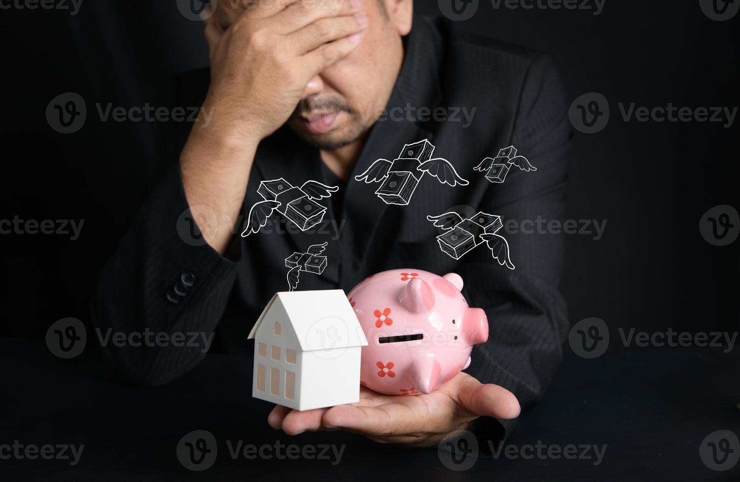 paper house and piggy bank on hand on black background, Businessman stressed about money to buy a new house, saving money concept photo