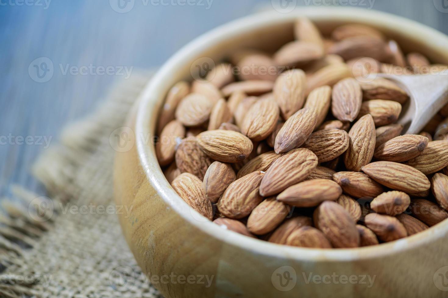 Almendras nuez y madera cuchara en madera taza en madera antecedentes. foto