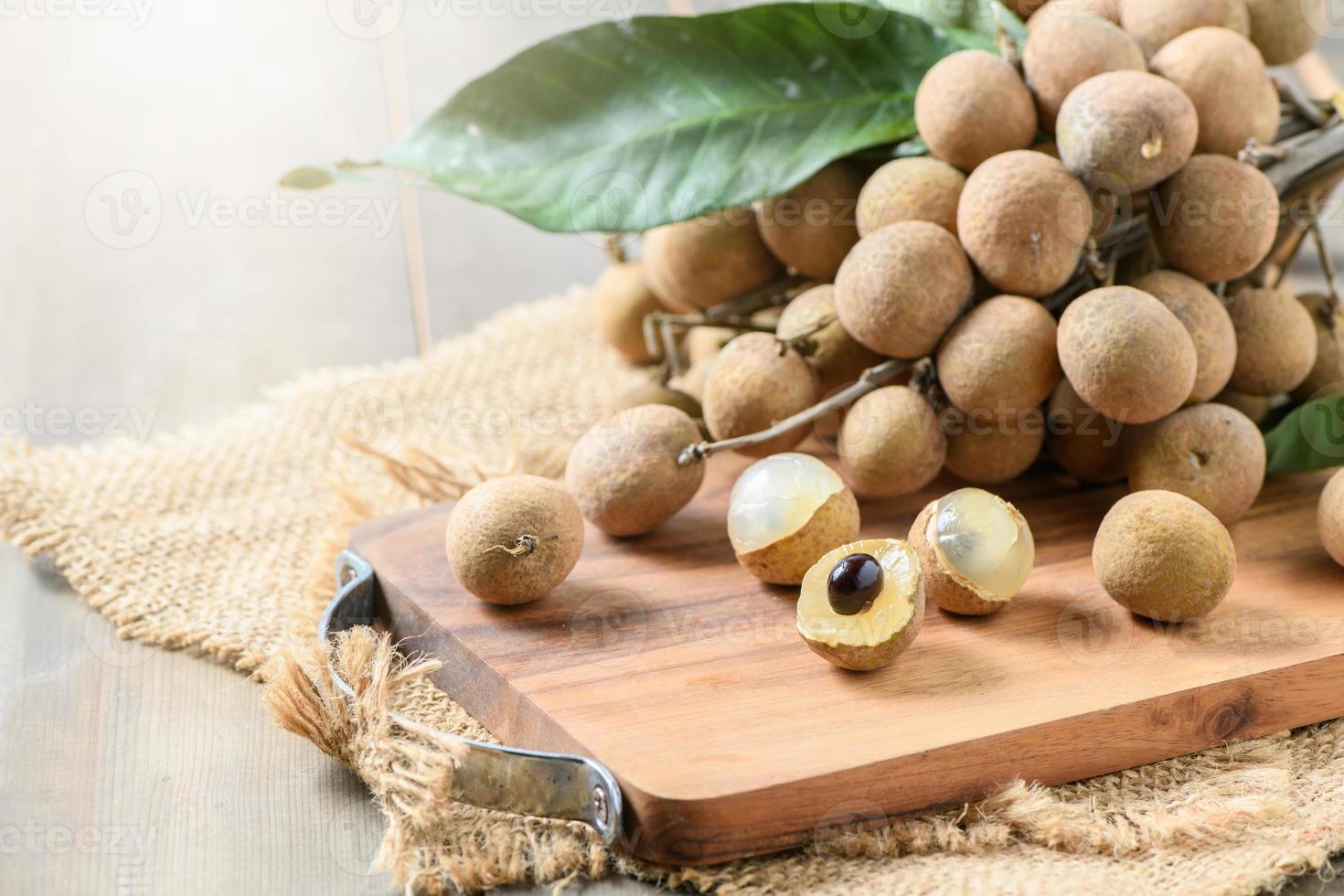 Fresh longan fruits on wood plate and old wood background, photo