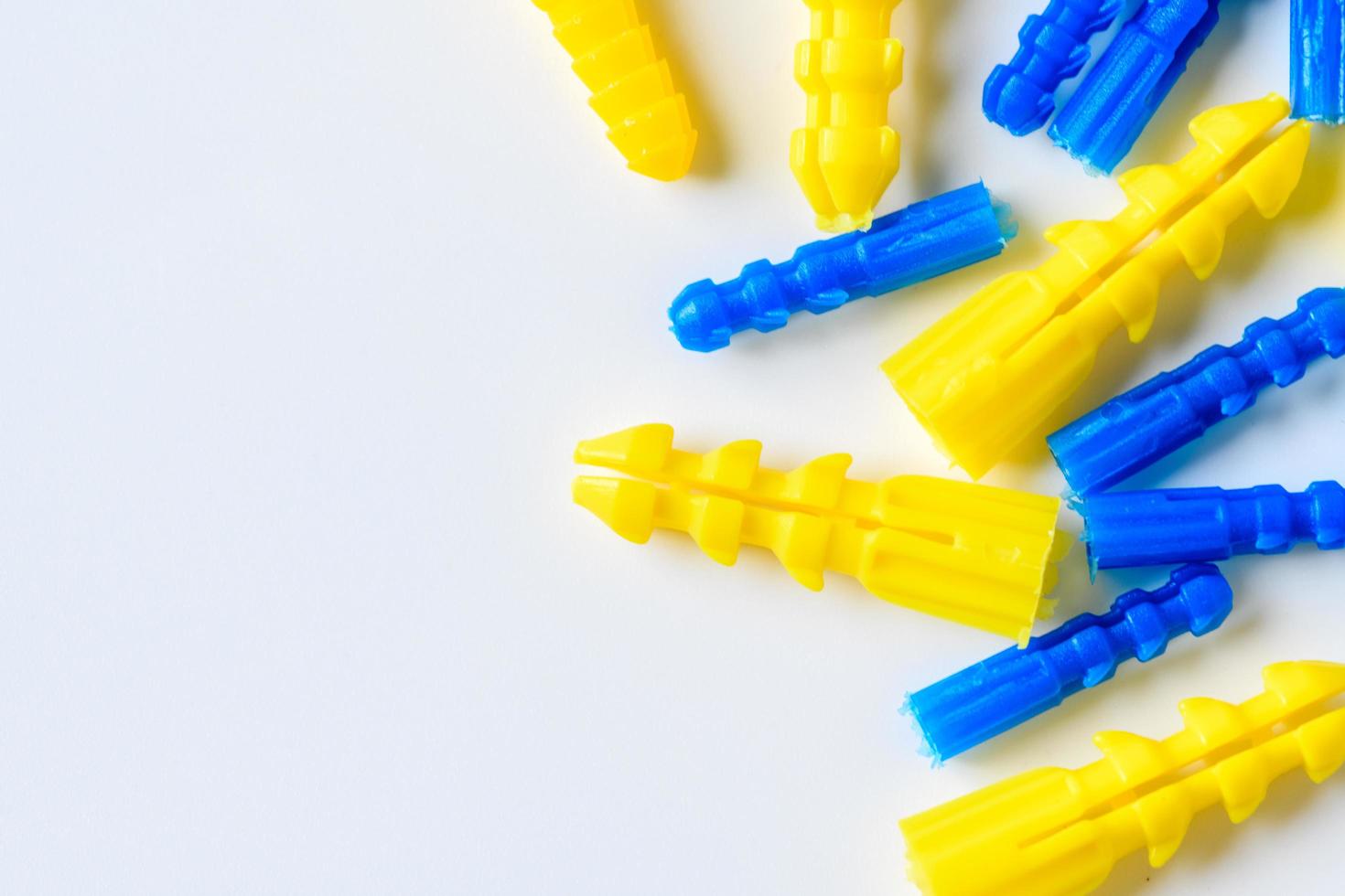 Yellow and blue plastic anchor on white background, Handyman Tools photo