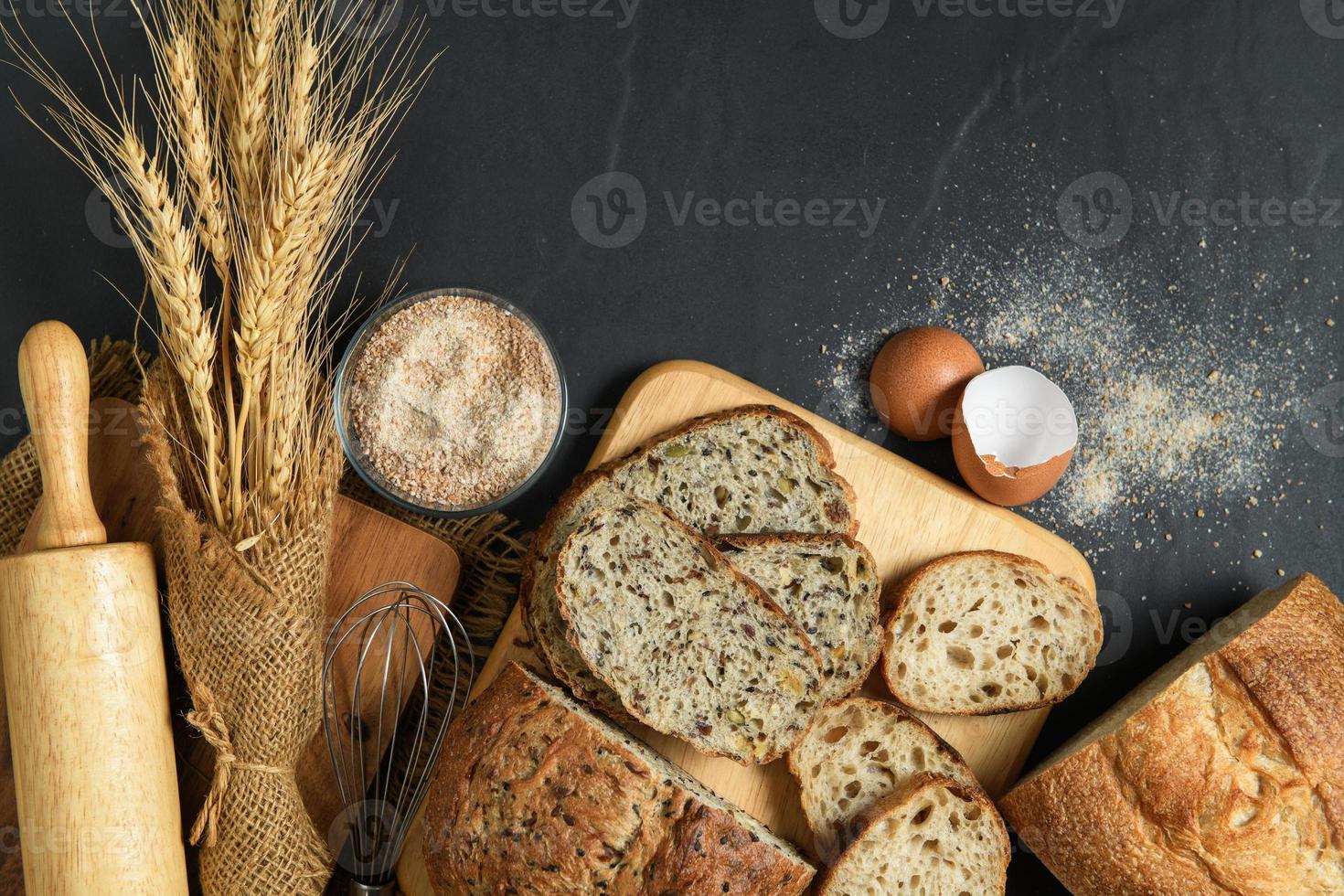 slide multi grain sourdough bread and sliced Baguette with Whole Wheat Flour on black stone background, photo
