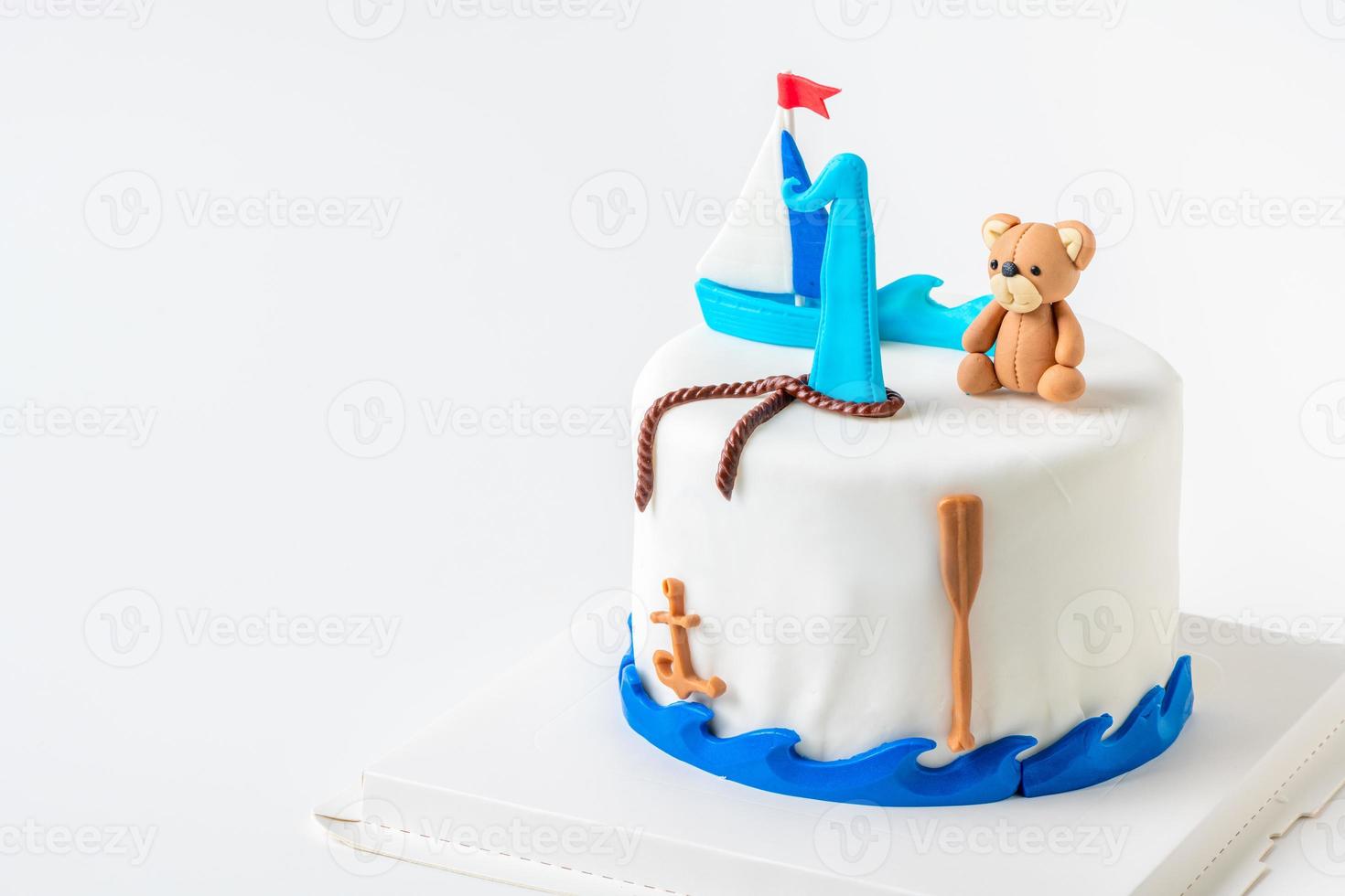 boat and doll bear fondant on vanilla cake on white background, photo