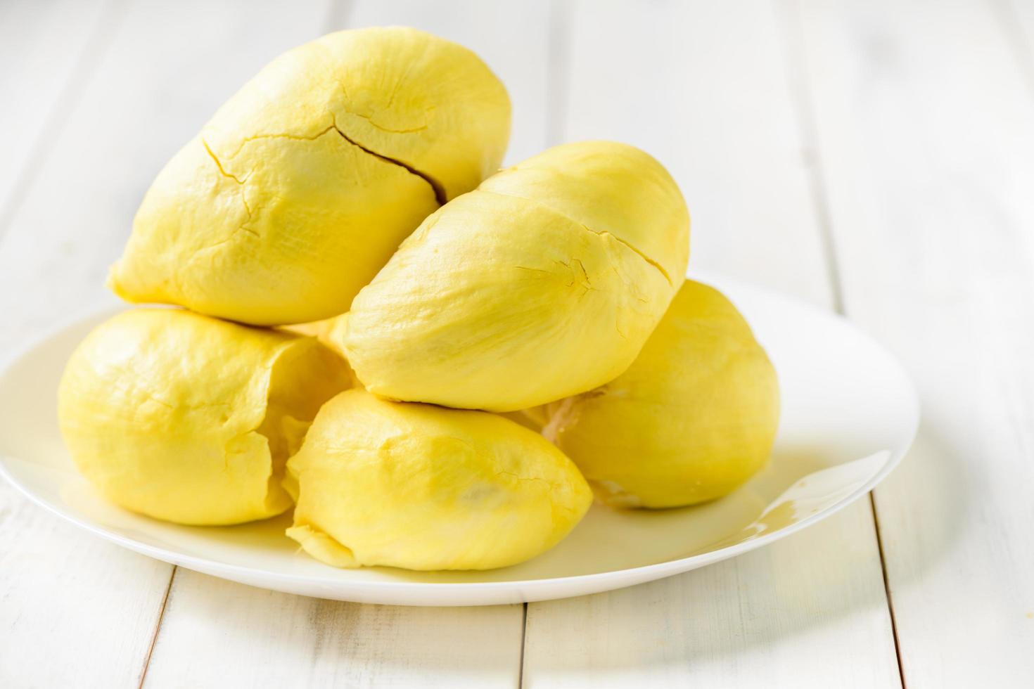 Fresco Durian meses en blanco plato y blanco madera fondo, Rey de Fruta desde Tailandia foto