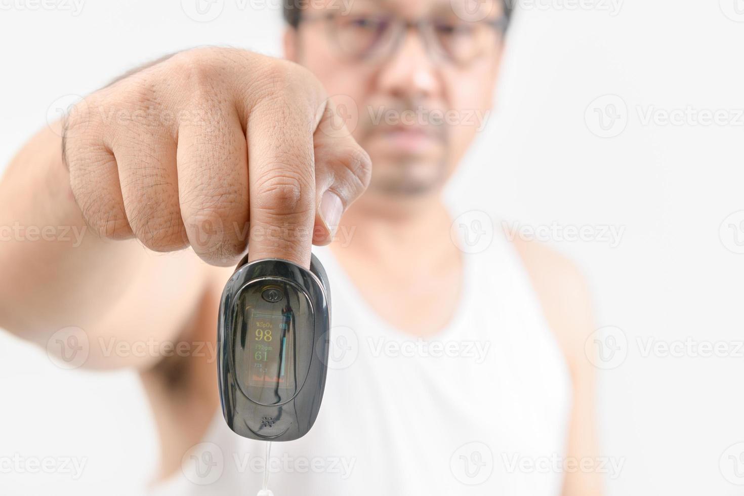 Hand of middle aged man with an attached pulse oximeter on fingertip photo