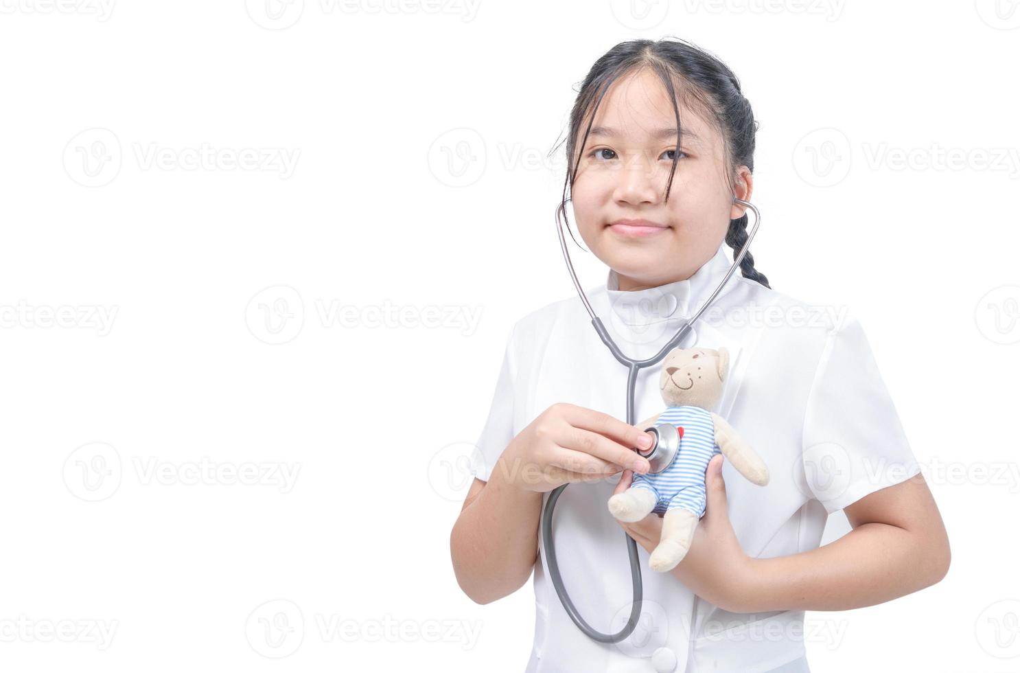 CUte little girl playing doctor and listening teddy bear with stethoscope isolated photo