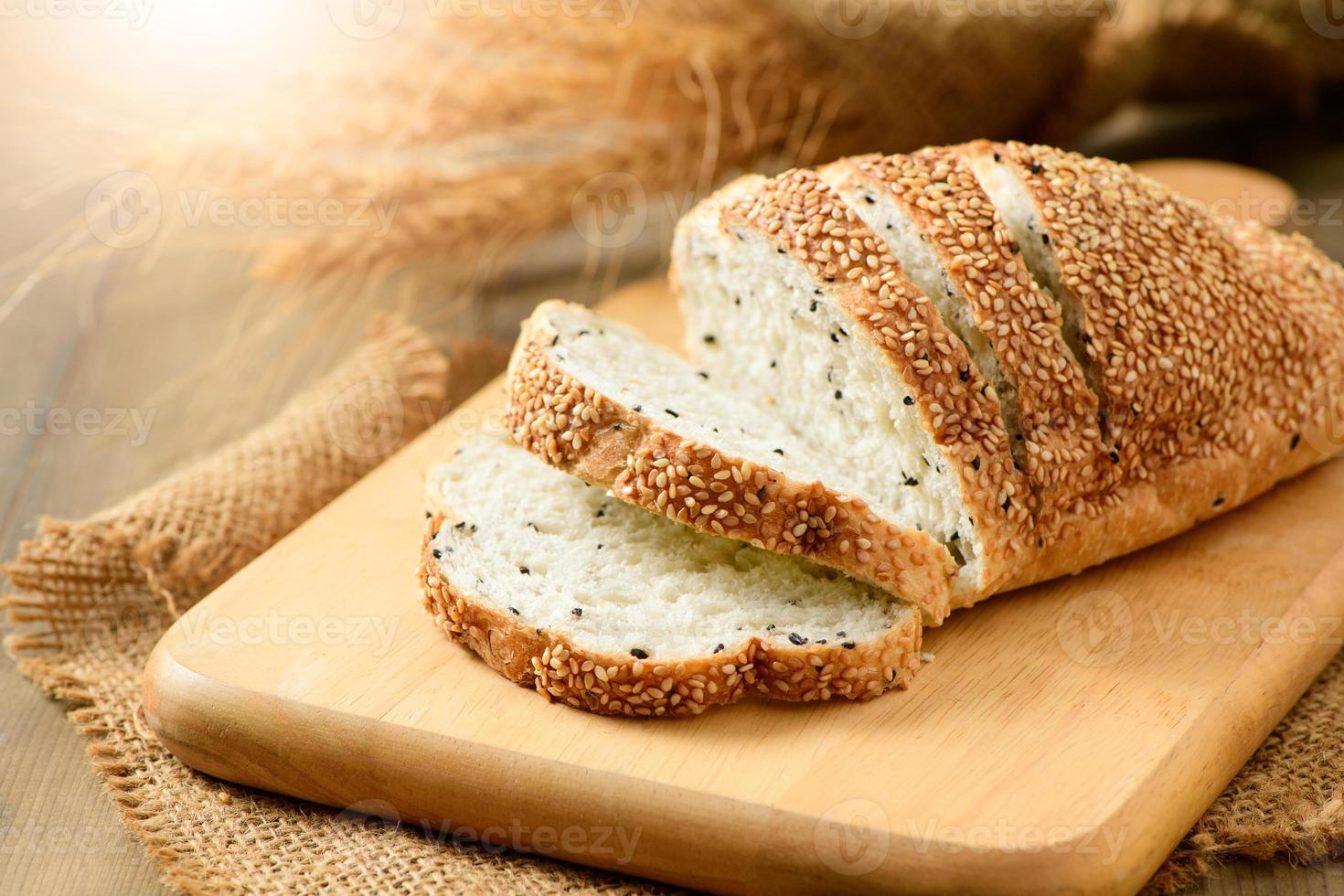 sliced french grain breads with white and black sesame on wood background photo