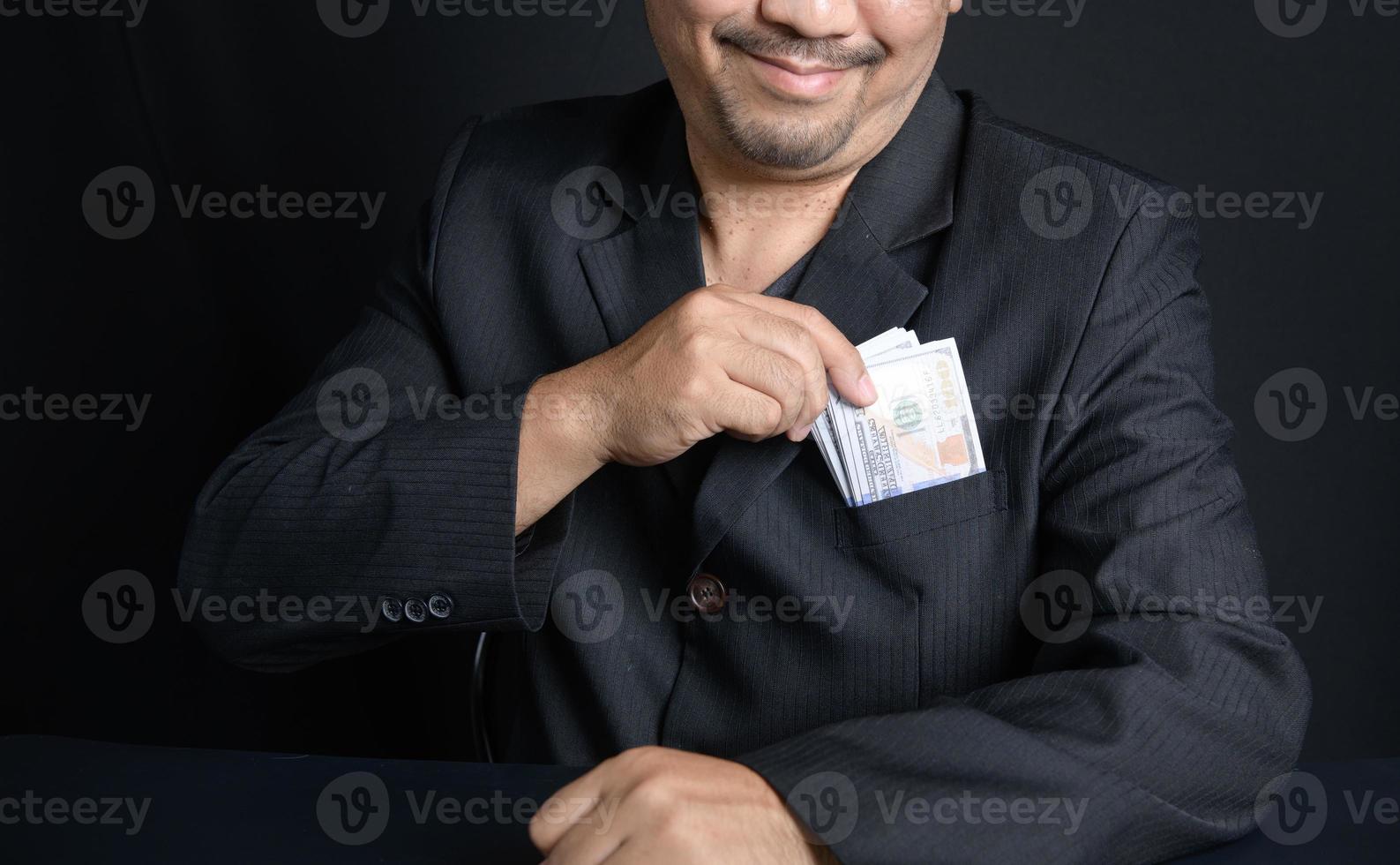 Man putting bribe money into pocket on black background, photo