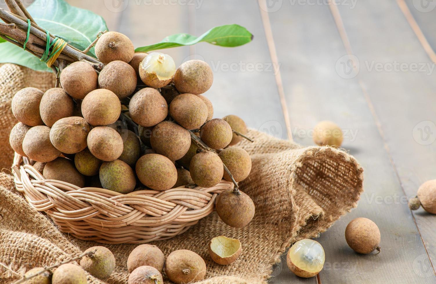 Fresh longan fruit with leaves in bamboo basket on wood photo