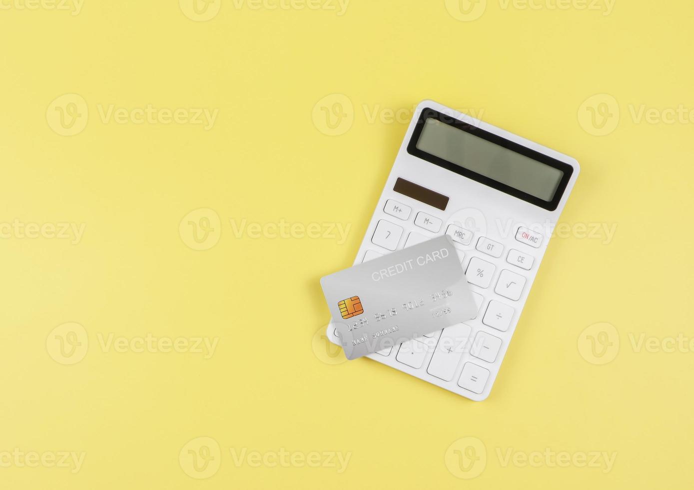 plano laico de blanco calculadora y crédito tarjeta en amarillo antecedentes con Copiar espacio. negocio y Finanzas concepto. foto