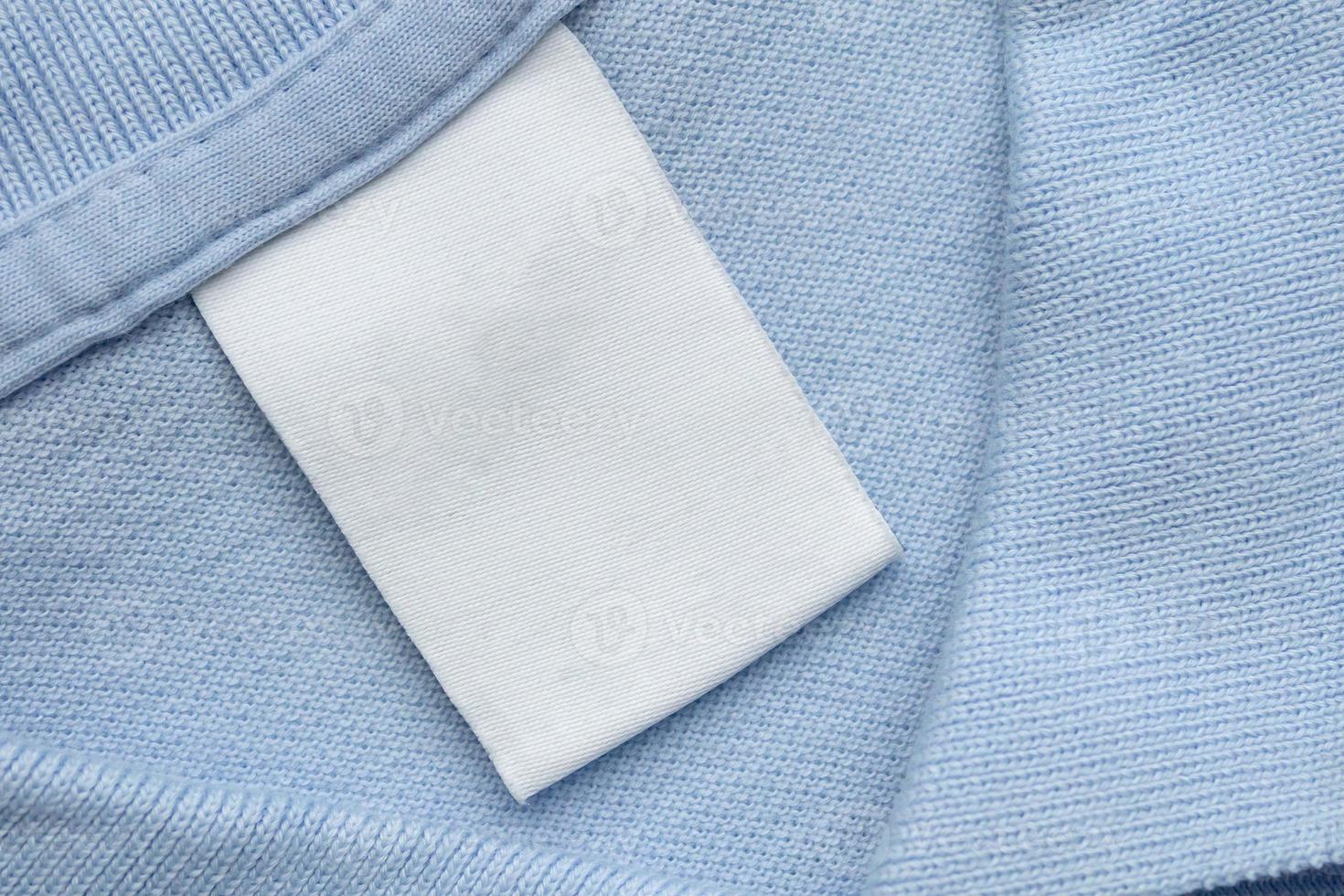 White blank laundry care clothes label on blue shirt fabric background photo