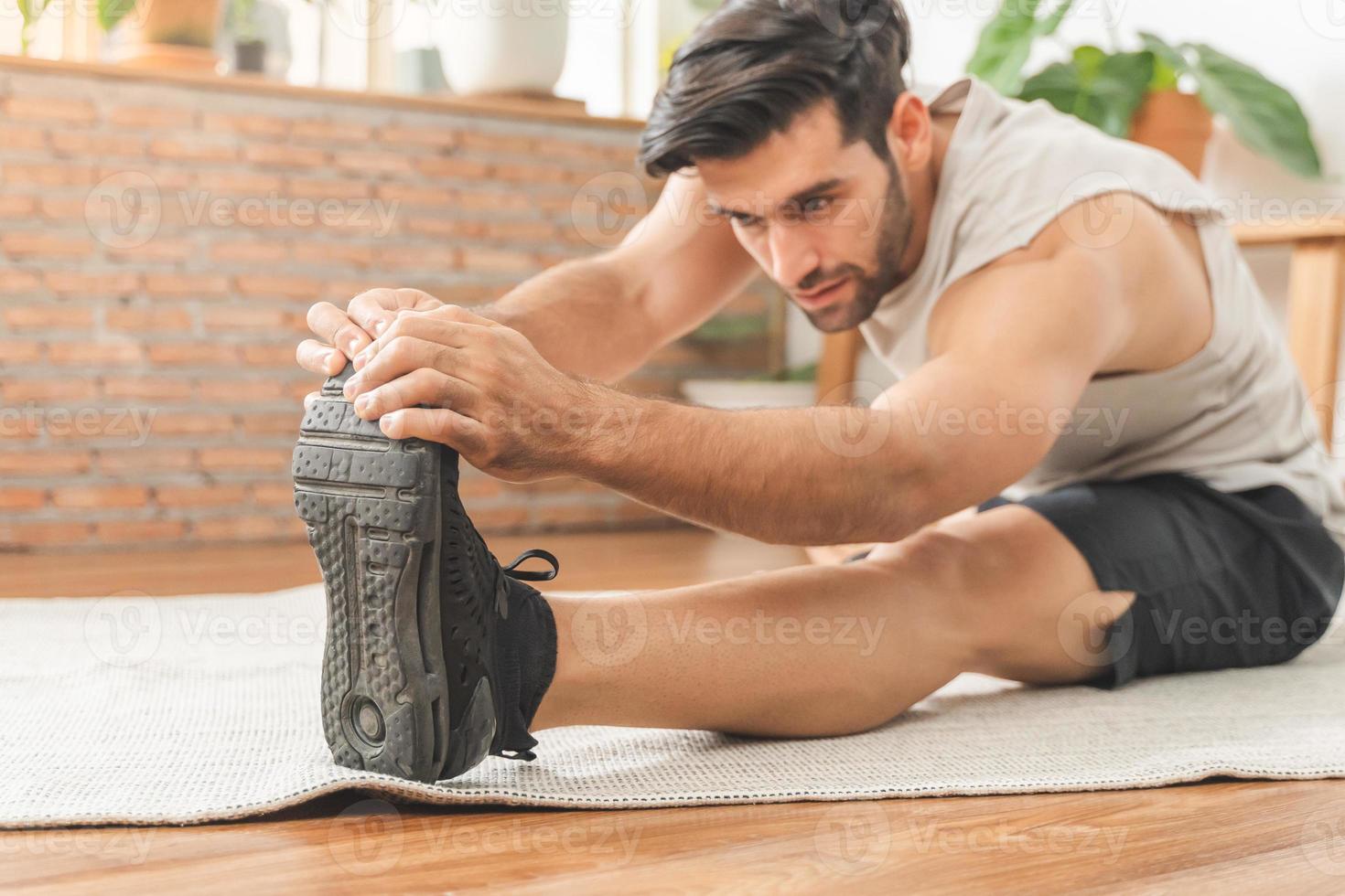 hermoso aptitud caucásico joven hombre mano en toque su dedo del pie, vistiendo ropa de deporte formación fuerza músculos ejercicio, ejercicio formación a hogar para sano cuerpo fuerte atlético, ajuste activo estilo de vida. foto