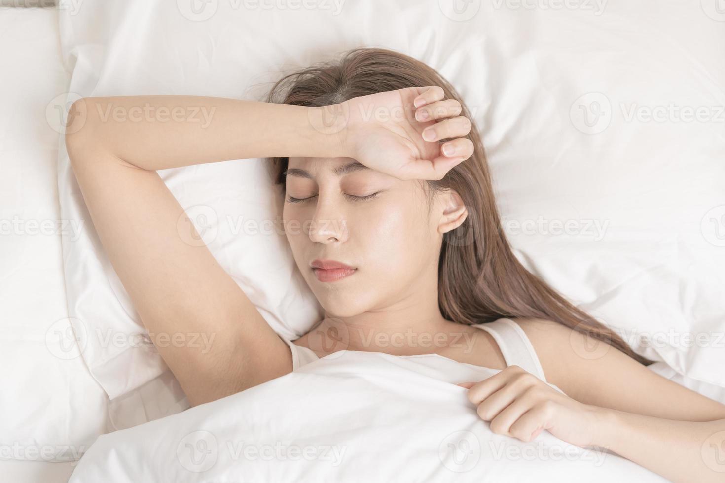 dulce Sueños, atractivo sonrisa bonito asiático joven mujer, niña dormido en cómodo cama acostado en suave almohada descansando, acuerdo ojos cerrado mientras con cubierto cobija en acogedor blanco cama en el Mañana. foto