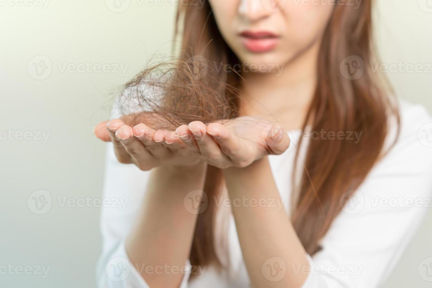 Serious, worried asian young woman, girl holding brush, show her comb, hairbrush with long loss hair problem after brushing, hair fall out on her hand in living room. Health care, beauty treatment. photo