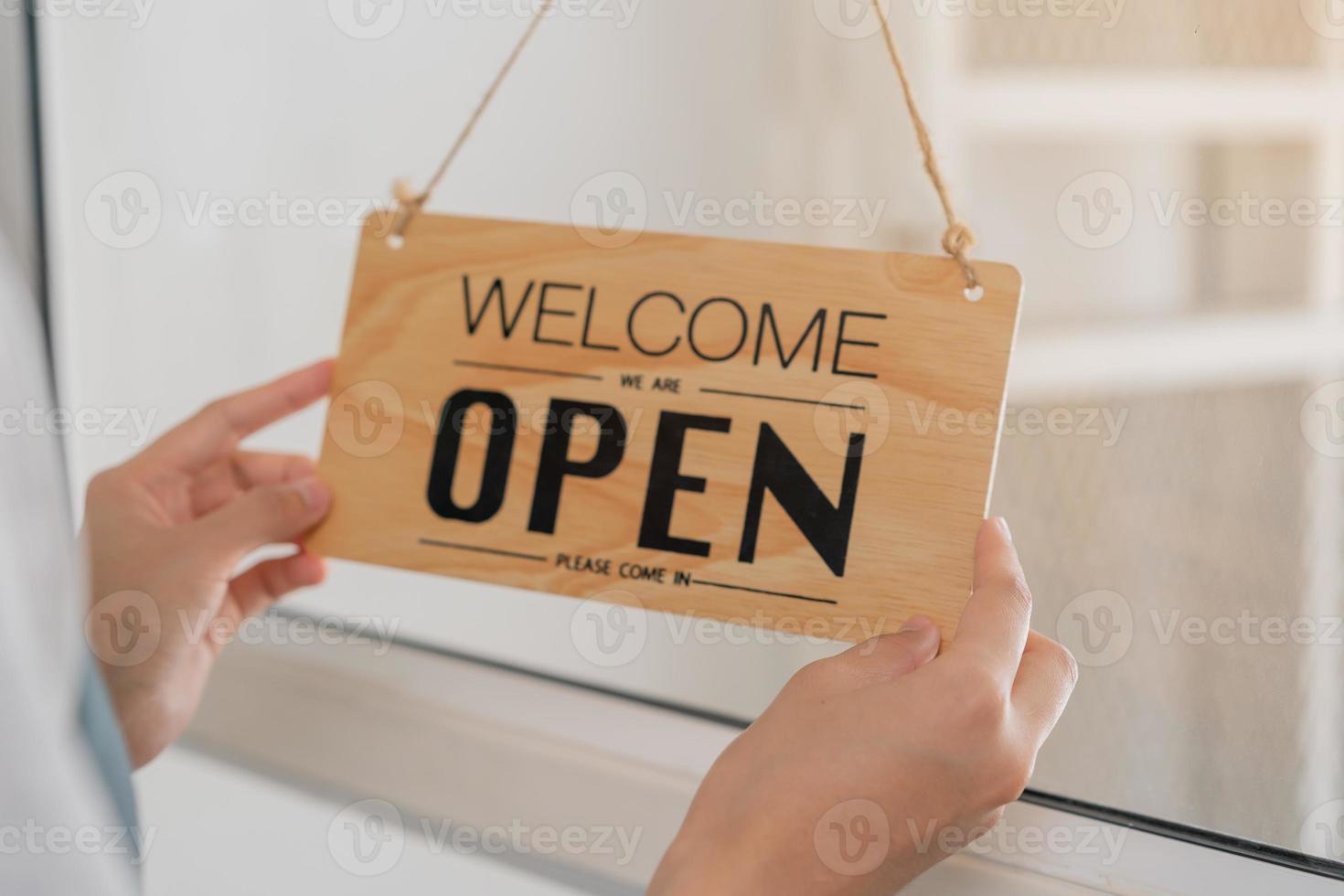 Owner business retail, asian young woman hand in turning sign board to open coffee shop, reopen store after close lockdown quarantine in covid-19. photo