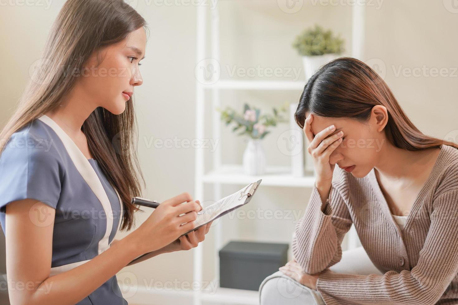 psicología, depresión. triste, sufrimiento asiático joven mujer consultante con psicólogo, psiquiatra mientras paciente asesoramiento mental con médico mujer tomando notas a clínica. alentador, terapia. foto