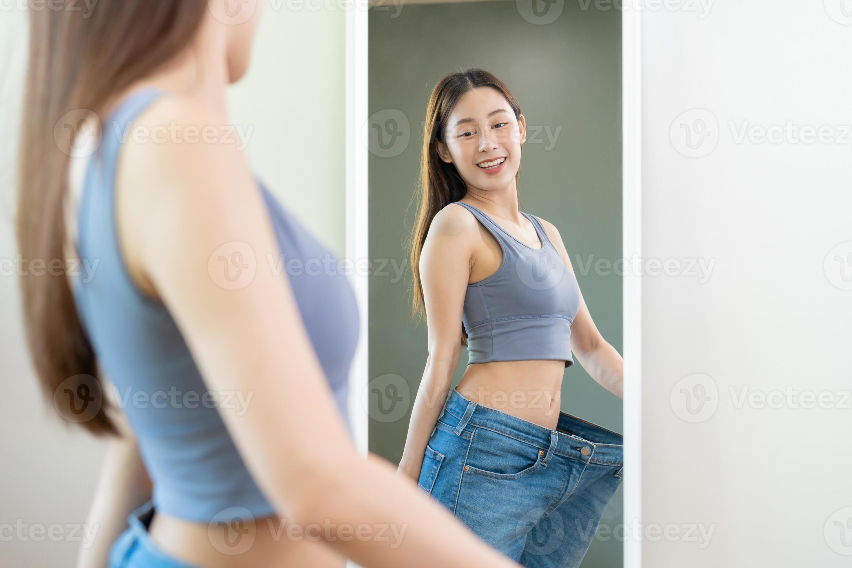 https://static.vecteezy.com/system/resources/previews/020/830/564/large_2x/shape-slender-thin-waist-attractive-slim-asian-young-woman-beautiful-girl-hand-show-shape-her-weight-loss-wearing-in-big-large-or-over-size-jeans-and-looking-into-mirror-people-body-fit-healthy-photo.jpg