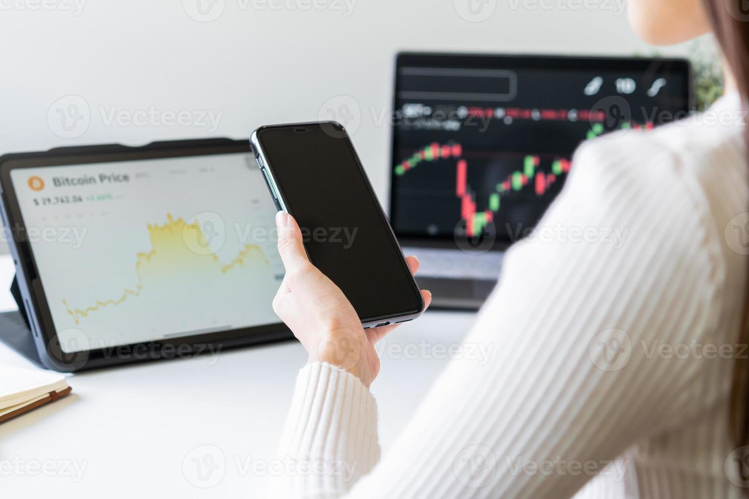 Investor analyzing exchange market, asian young business woman trader on graphic charts on laptop computer, hand in using smartphone for trading stock, looking at screen with diagrams at home office. photo