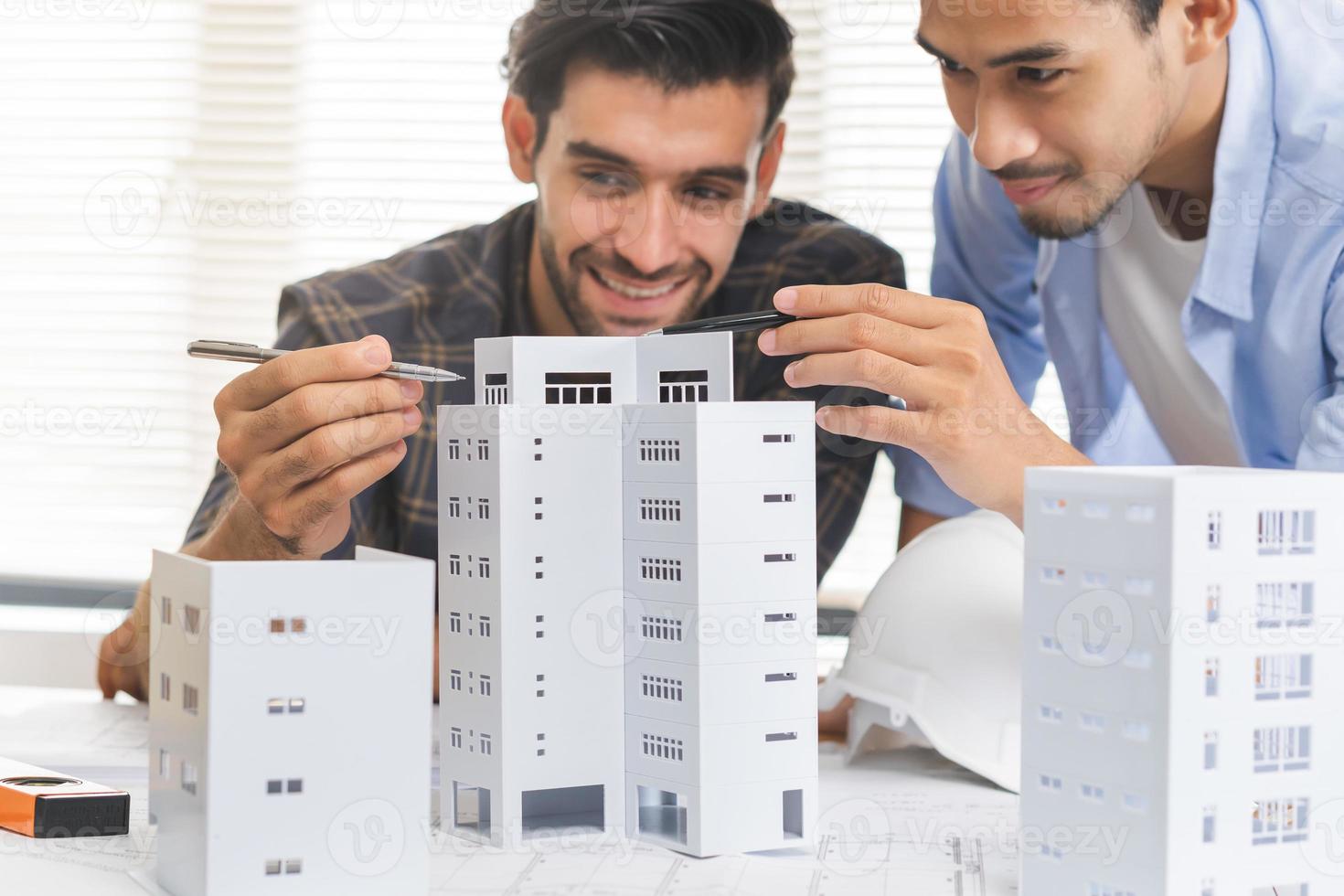 Construction of Engineer, architect businessman, man hand making on 3D model house building in office together, meeting plan working with partner team colleague on blueprint, discussing design project photo