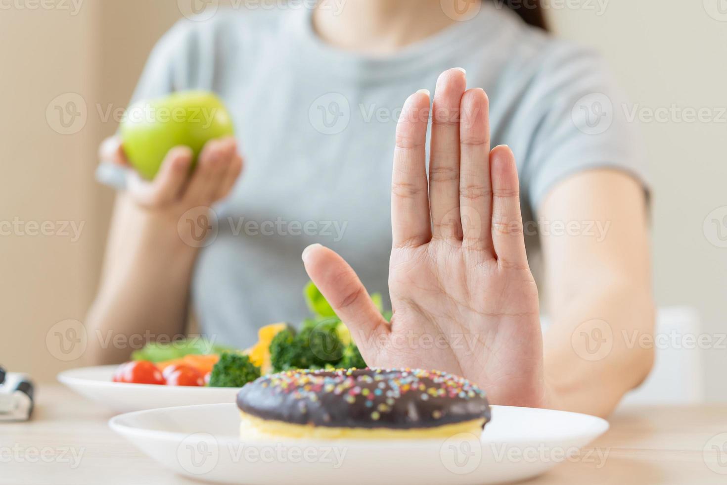 Diet, Dieting asian young woman or girl use hand push out, deny sweet donut and choose green salad vegetables, eat food for good healthy, health when hungry. Close up female weight loss person. photo