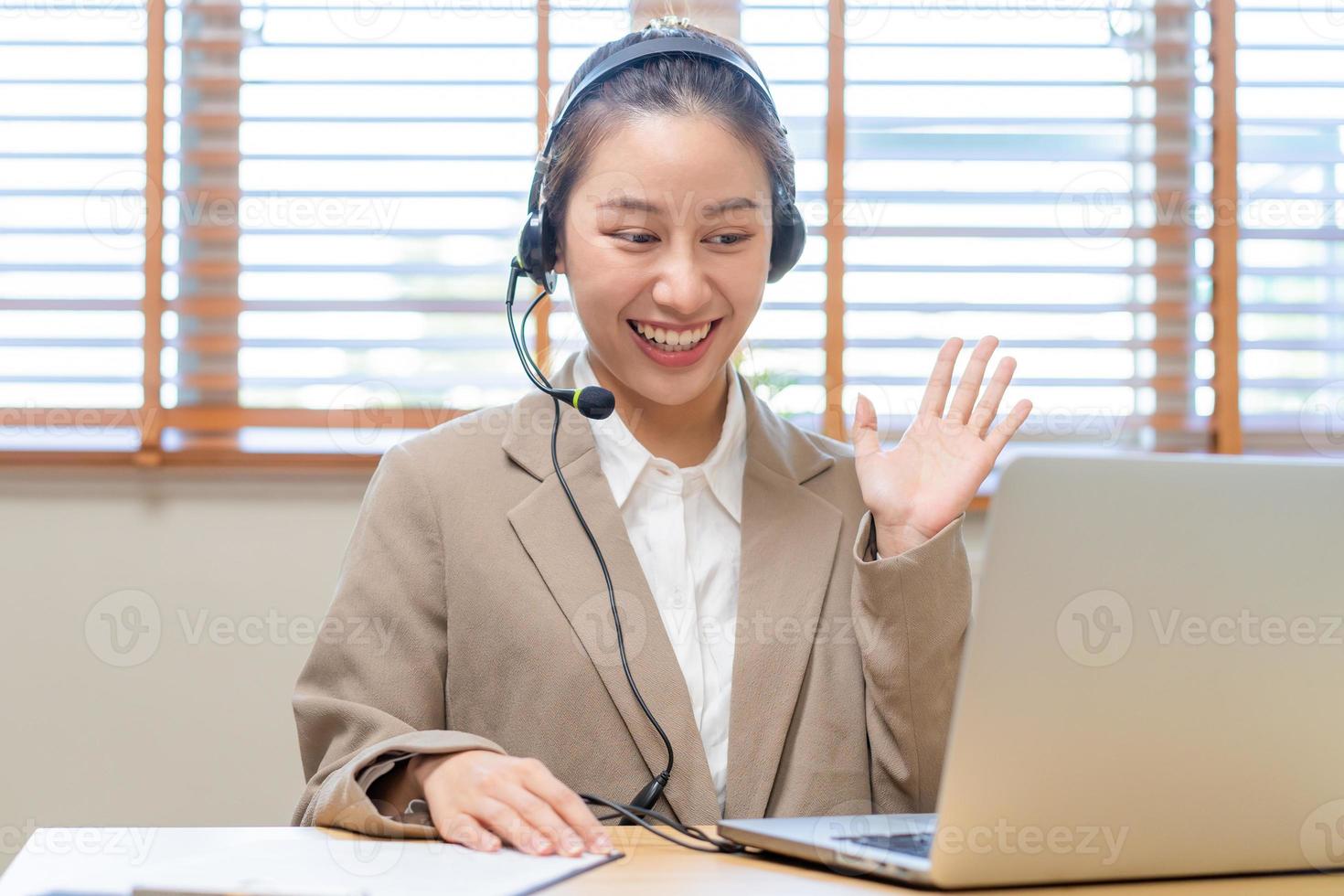 Operator asian young woman wearing headset, headphones and speaking on video call conference with customer, colleagues support phone, work on laptop computerTechnology of help, consult service photo