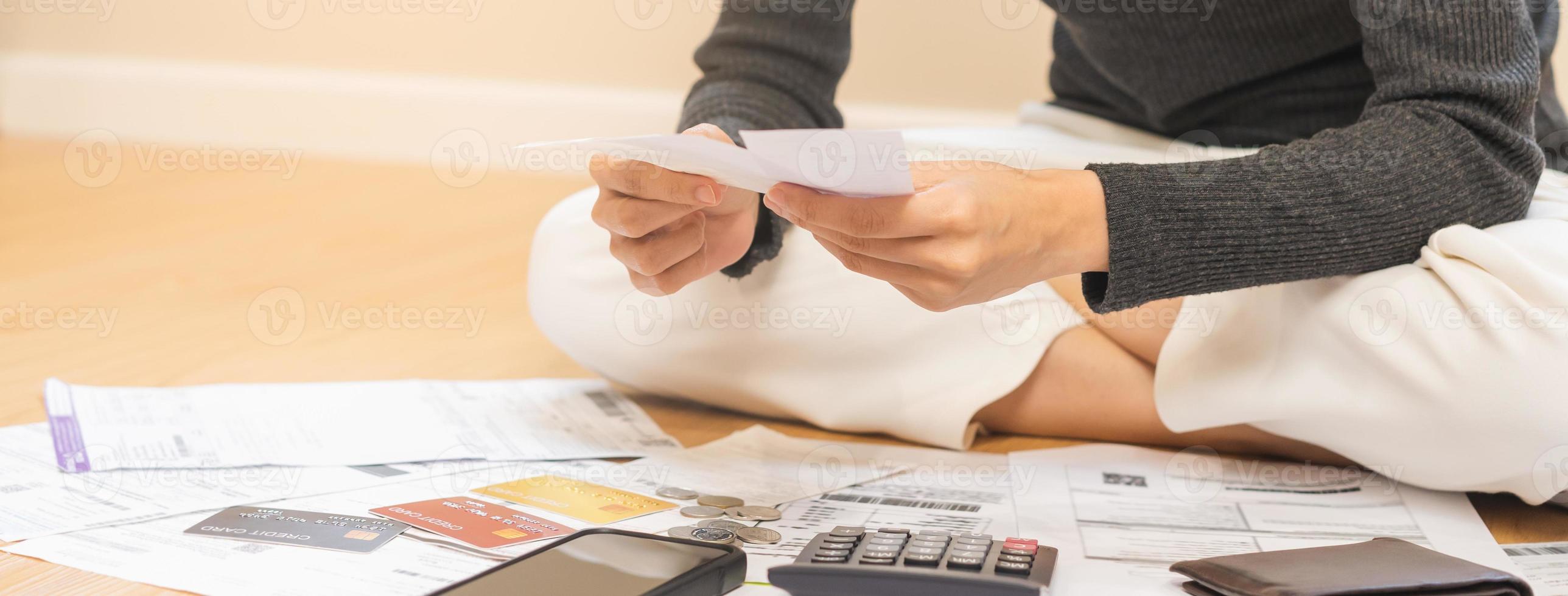 Financial owe asian woman, girl sitting on floor at home, stressed and confused by calculate expense, hand holding bill, have no money to pay, mortgage or loan. Debt, bankruptcy or bankrupt concept. photo