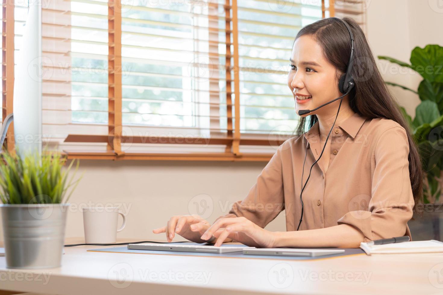 Video call, meeting conference via camera, happy pretty asian young woman, girl sitting, wear wireless headphone study online, using laptop computer, freelancer working.Technology, social distance. photo