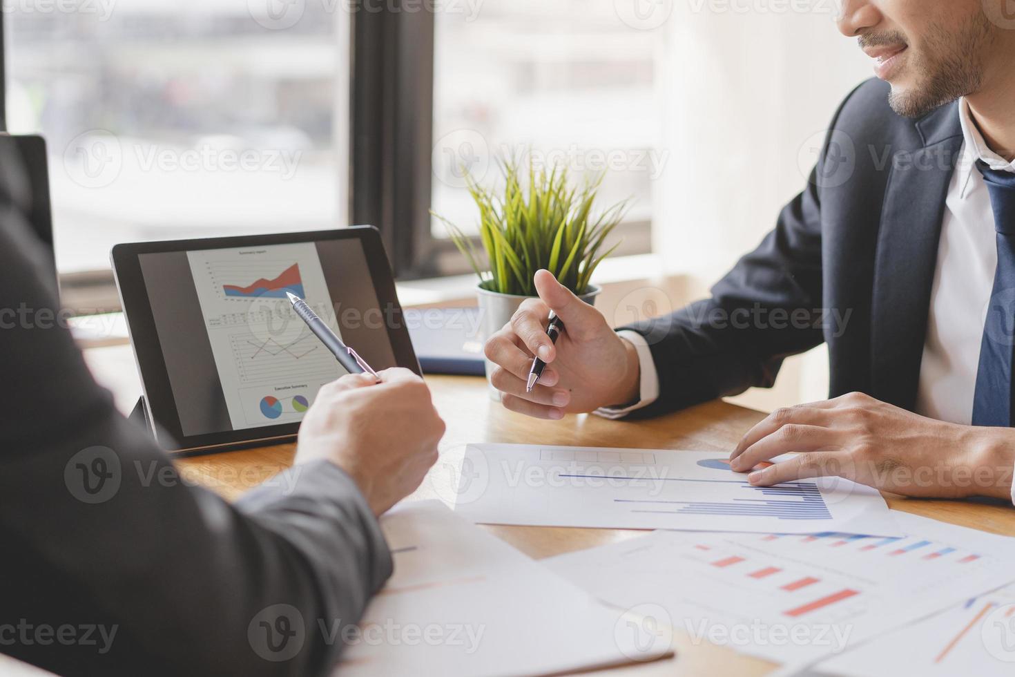 Business meeting, two caucasian, asian group man use tablet brainstorm analyzing on graph data of cost plan or document, paperwork and discussing in board room on table. People working conference room photo