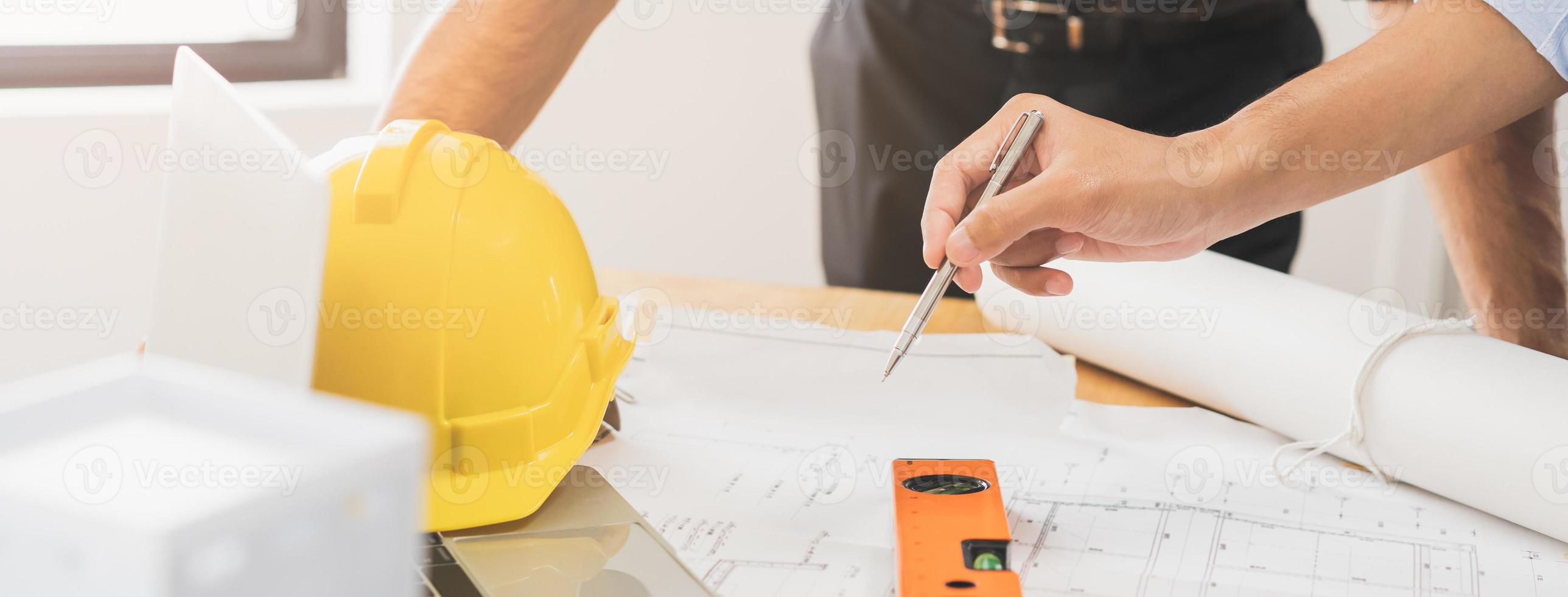 construcción de ingeniero, arquitecto joven empresario, colega masculino mano en utilizar bolígrafo punto a Plano papel en oficina, reunión plan trabajando con compañero equipo edificio, que se discute diseño proyecto. foto