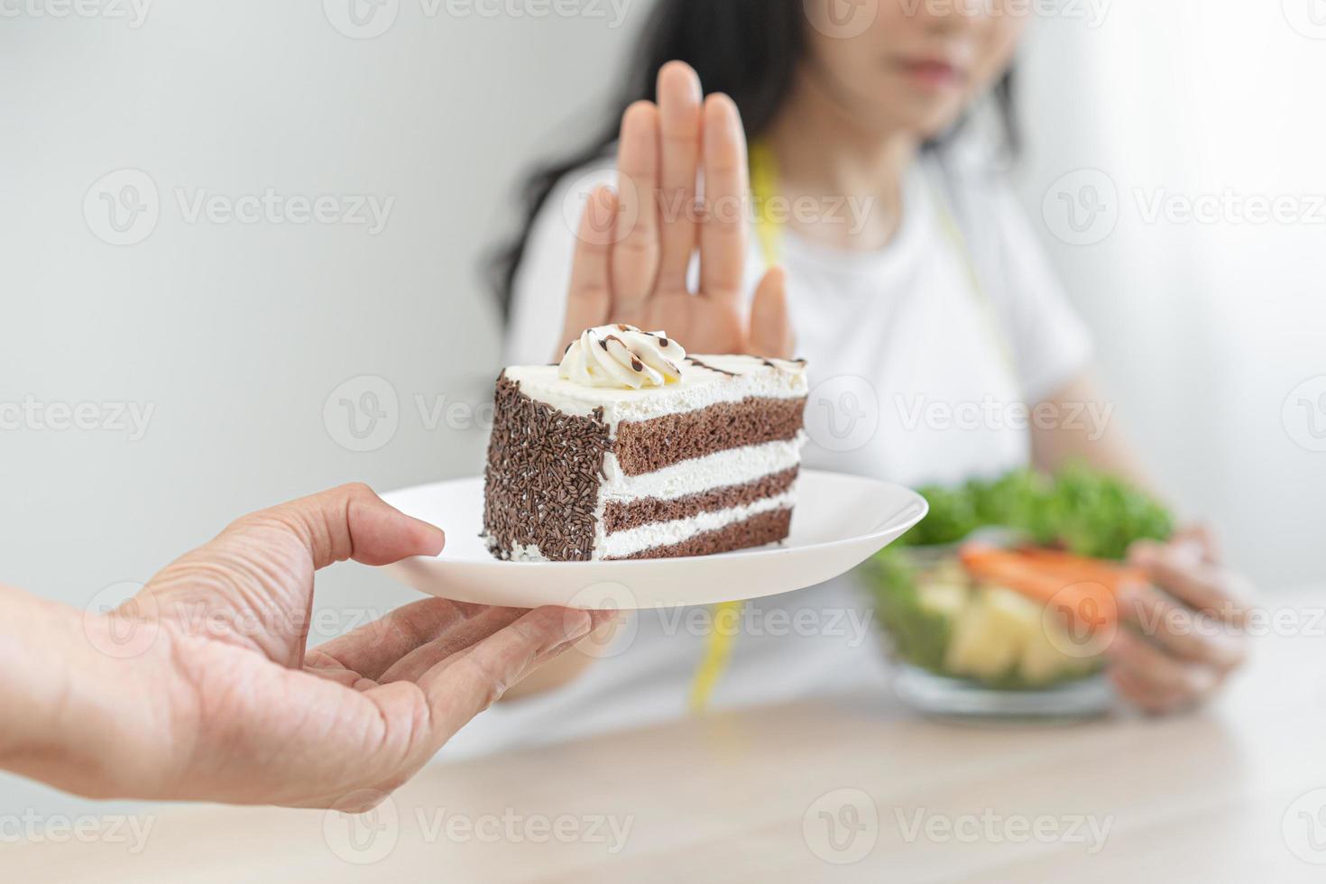 Diet, Dieting unhealthy asian young woman hand in push out, rejecting eat chocolate cake or sweet taste, fighting to keep it from getting fat when person bring to me. Healthy, nutrition of weight loss photo